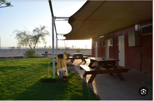 a picnic table and benches under a tent at בית ספר שדה חצבה in H̱aẕeva