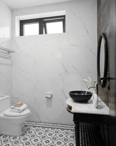 a white bathroom with a toilet and a sink at The Gate Boutique Hotel Đà Lạt in Da Lat