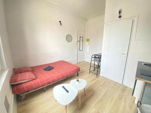 Cette petite chambre comprend un lit rouge et une table. dans l'établissement Le mimosa T, à Amiens