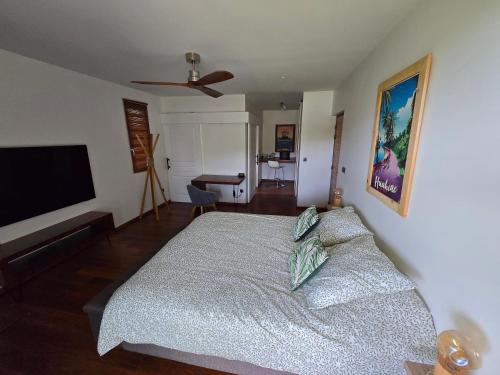 a bedroom with a bed and a flat screen tv at TITOU LODGE - Hauteurs de Miri in Punaauia