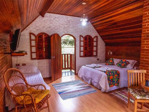 Un dormitorio con una cama en una habitación con techos de madera. en Pousada Monjolos de Minas a 9 km de Gonçalves, en Gonçalves
