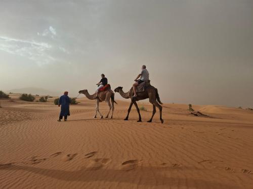 two people riding on camels in the desert at Morocco Deluxe Camp - Assif n'Itrane in Lac Yasmins