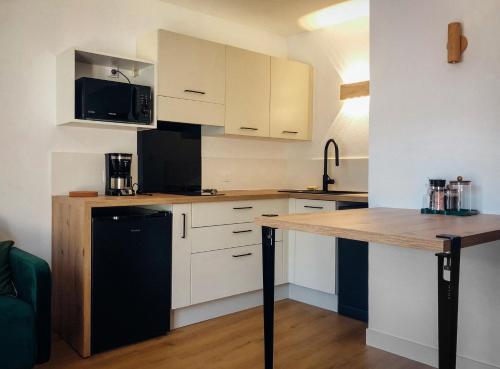 une cuisine avec des armoires blanches et un comptoir en bois dans l'établissement Cano'Py, charmant 2 pièces avec vue montagne en cœur de ville, à Luchon