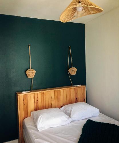 - une chambre dotée d'un mur vert et d'un lit avec des oreillers blancs dans l'établissement Cano'Py, charmant 2 pièces avec vue montagne en cœur de ville, à Luchon