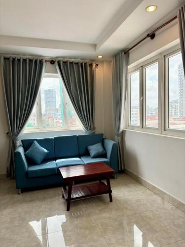 ein Wohnzimmer mit blauem Sofa und Fenstern in der Unterkunft ST Apartment in Phnom Penh