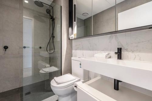 a bathroom with a toilet and a sink and a shower at Sunlit & Sleek Condo in Lively St Kilda in Melbourne