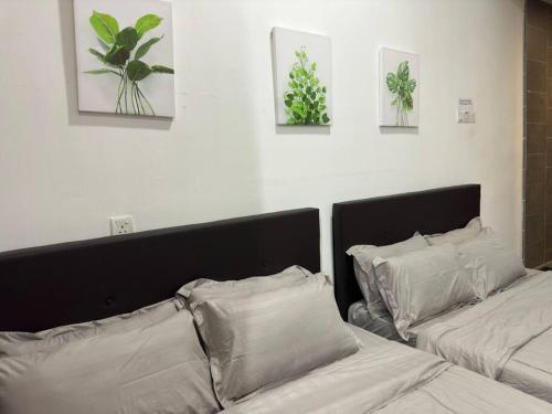 a bedroom with two beds with pillows and pictures on the wall at Cozy 5pax AndroidTVBOX Free Parking WiFi 1U PJPAC in Kampong Bukit Lanjan