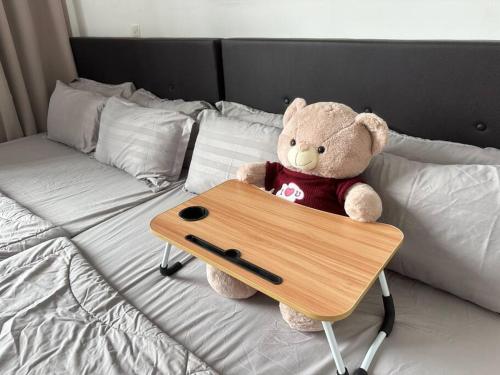 a teddy bear sitting on a bed with a table at Cozy 5pax AndroidTVBOX Free Parking WiFi 1U PJPAC in Kampong Bukit Lanjan