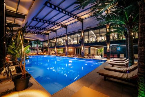 a large swimming pool with chairs and a building at Hotel Nordic Twins & Wellness in Rădăuţi