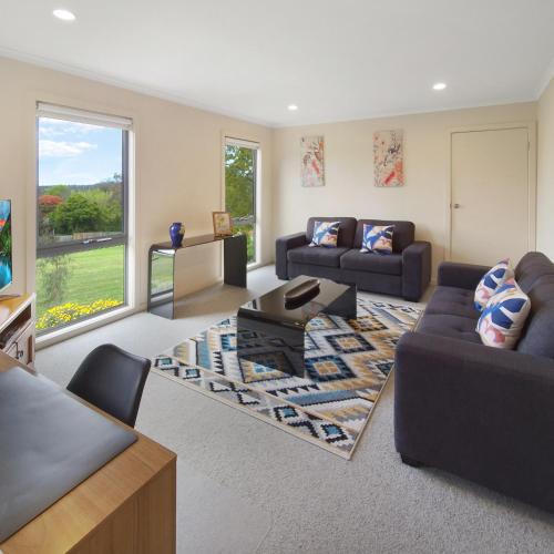 a living room with two couches and a table at Bungunyah Apartments in Croydon