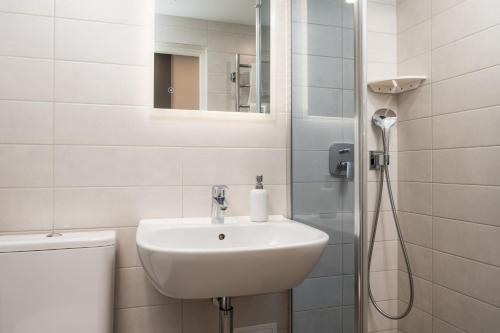 a white bathroom with a sink and a shower at Hotel Vesiroos in Pärnu