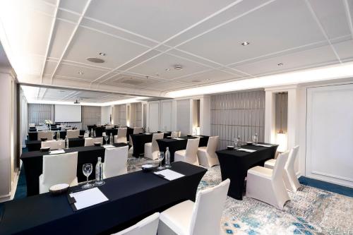 a large room with tables and white chairs at Mövenpick Myth Hotel Patong Phuket in Patong Beach