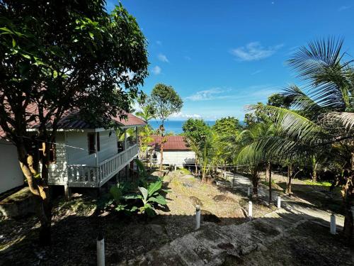 a white house with a porch and trees at Nice Beach Bungalow in Koh Rong Island