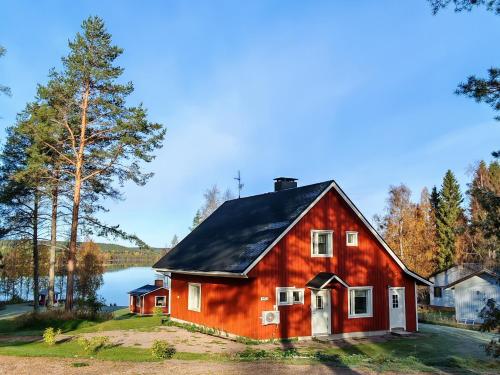 a red barn with a lake in the background at Villa Haaveranta - Private Villa by the lake in Rovaniemi