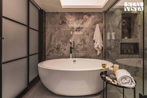 a bathroom with a large tub and a shower at StayVista at Grande Prima - Pool, Theatre Room & BBQ in Panchgani