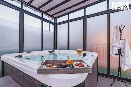 a jacuzzi tub with a plate of food and a wine glass at StayVista at Grande Prima - Pool, Theatre Room & BBQ in Panchgani