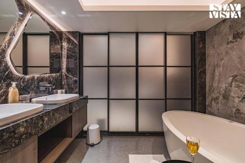 a bathroom with two sinks and a tub and a mirror at StayVista at Grande Prima - Pool, Theatre Room & BBQ in Panchgani