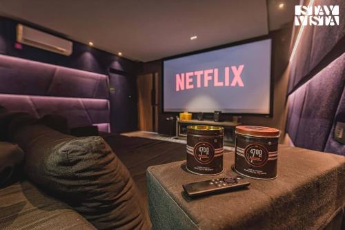 two coffee cups on a table in front of a television at StayVista at Grande Prima - Pool, Theatre Room & BBQ in Panchgani