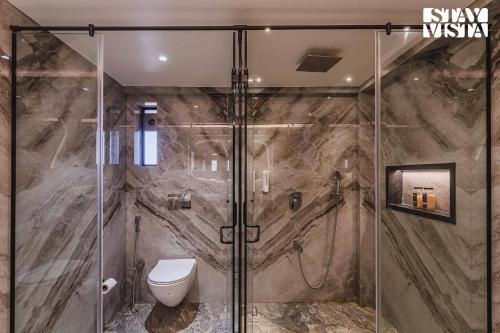 a bathroom with a glass shower with a toilet at StayVista at Grande Prima - Pool, Theatre Room & BBQ in Panchgani