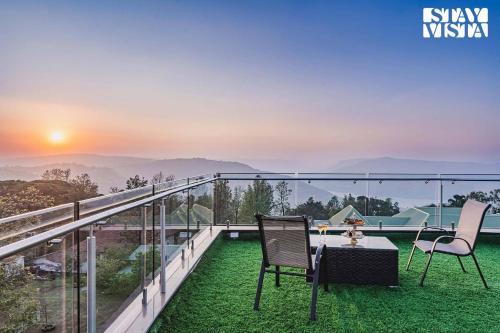 a balcony with two chairs and a table with a view at StayVista at Grande Prima - Pool, Theatre Room & BBQ in Panchgani