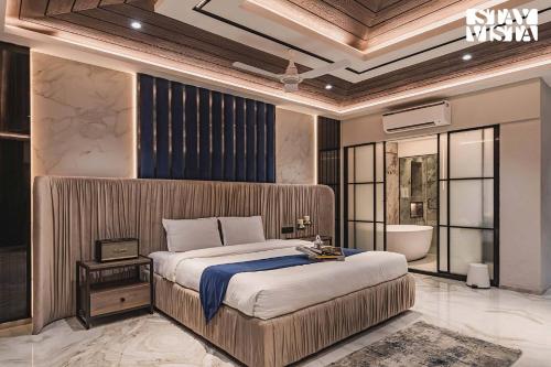 a bedroom with a large bed and a bath room at StayVista at Grande Prima - Pool, Theatre Room & BBQ in Panchgani