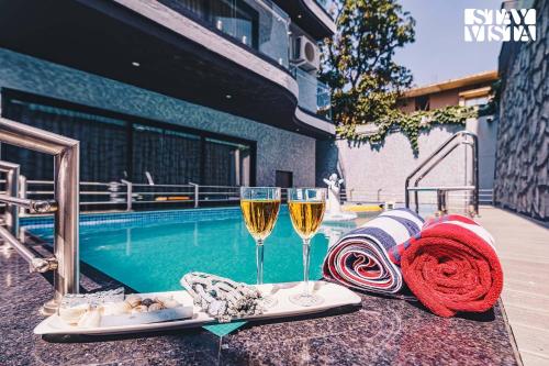two glasses of champagne next to a swimming pool at StayVista at Grande Prima - Pool, Theatre Room & BBQ in Panchgani