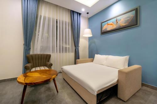 a bedroom with a bed and a chair at Full Moon Apartments & Villa - Hoi An in Hoi An