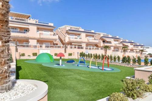 un appartement avec une aire de jeux en face d'un bâtiment dans l'établissement Vista Azul Spa Resort, à Punta Prima