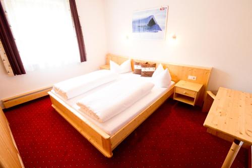 ナウダースにあるHaus Priethのベッドルーム1室(赤いカーペット敷きの大型ベッド1台付)