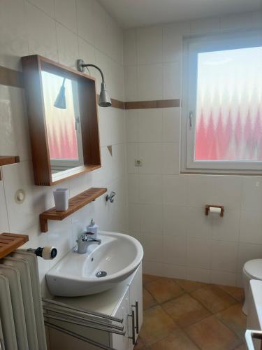 a white bathroom with a sink and a window at A&D Monteurzimmer Ferienwohnung in Bad Mergentheim