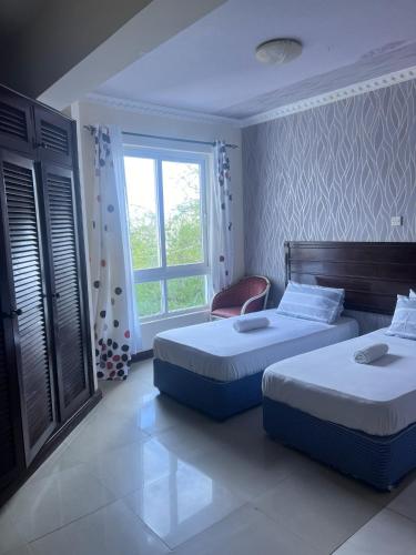 a bedroom with two beds and a window at Sunrise Nyali in Nyali