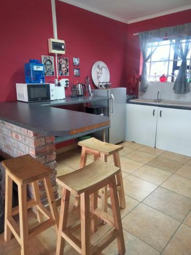 a kitchen with a counter and two stools in it at Addo's Secret Backdoor in Gqeberha