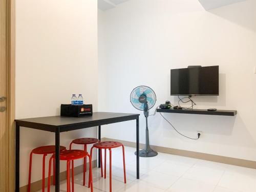a table with two red stools and a fan at Fancy and Nice 2BR at Tokyo Riverside PIK 2 Apartment By Travelio in Rawalembang