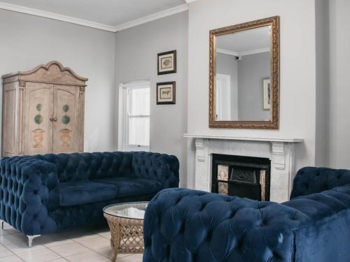 a living room with blue couches and a mirror at Craigrownie Luxury Guest House in Cape Town