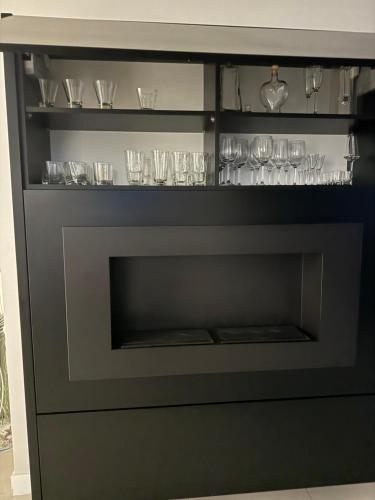 a black entertainment center with glasses and wine glasses at Spanko w centrum in Zielona Góra