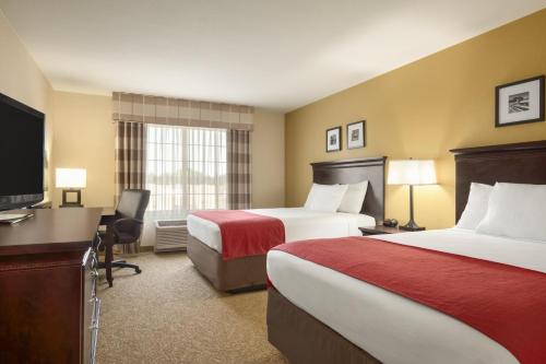 a hotel room with two beds and a flat screen tv at Country Inn & Suites by Radisson, Minot, ND in Minot