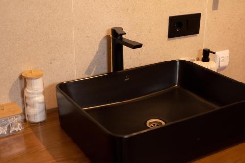 a black sink with a faucet in a bathroom at Dobrede - будиночки під лісом in Dubrynychi