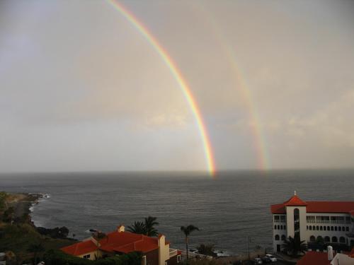 a rainbow in the sky over the ocean at Apartment Palma Madeira wandern und tauchen in Caniço