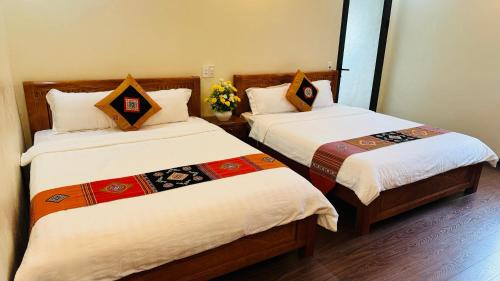 a room with two beds with white sheets at Sapa Harmony Homestay in Sapa