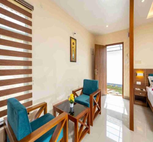 a living room with two chairs and a table and a bed at Le Serene Munnar Luxury Resorts & Spa in Ūdumbanshola