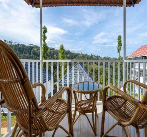 a porch with two chairs and a table at Le Serene Munnar Luxury Resorts & Spa in Ūdumbanshola