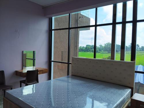 a room with a bed and a large window at Hotel palash in Silwai