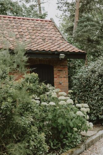 a brick house with a garden with white flowers at Restaries at Paradise Farm in Halesworth