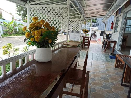 un jarrón de flores amarillas sentado en una mesa de madera en RainBow House Resort, en Kamphaeng Phet
