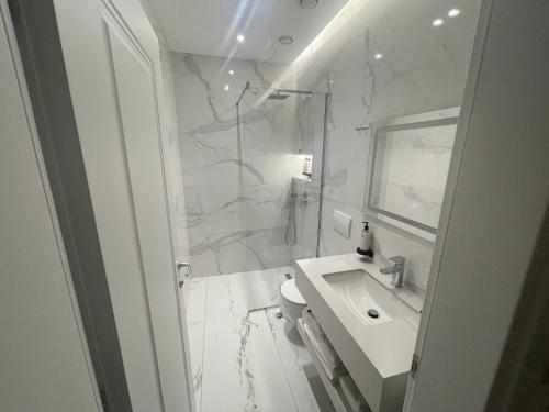 a white bathroom with a sink and a mirror at Seaside Hotel in Vlorë