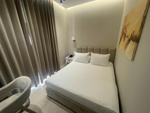 a small bedroom with a white bed and a chair at Seaside Hotel in Vlorë