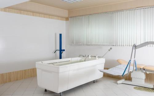 a white bathroom with a tub and a chair at Gashalti Health Hotel Naftalan in Naftalan