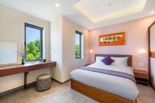 a bedroom with a bed and a desk and windows at Full Moon Apartments & Villa - Hoi An in Hoi An