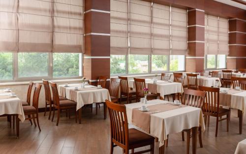 a dining room with tables and chairs and windows at Gashalti Health Hotel Naftalan in Naftalan