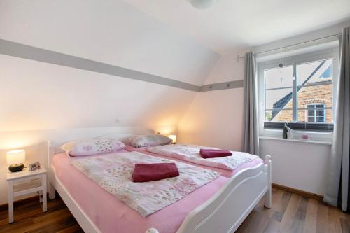 a bedroom with a bed with pink sheets and a window at Ferienwohnung Ingwersen Nordstrand in Nordstrand
